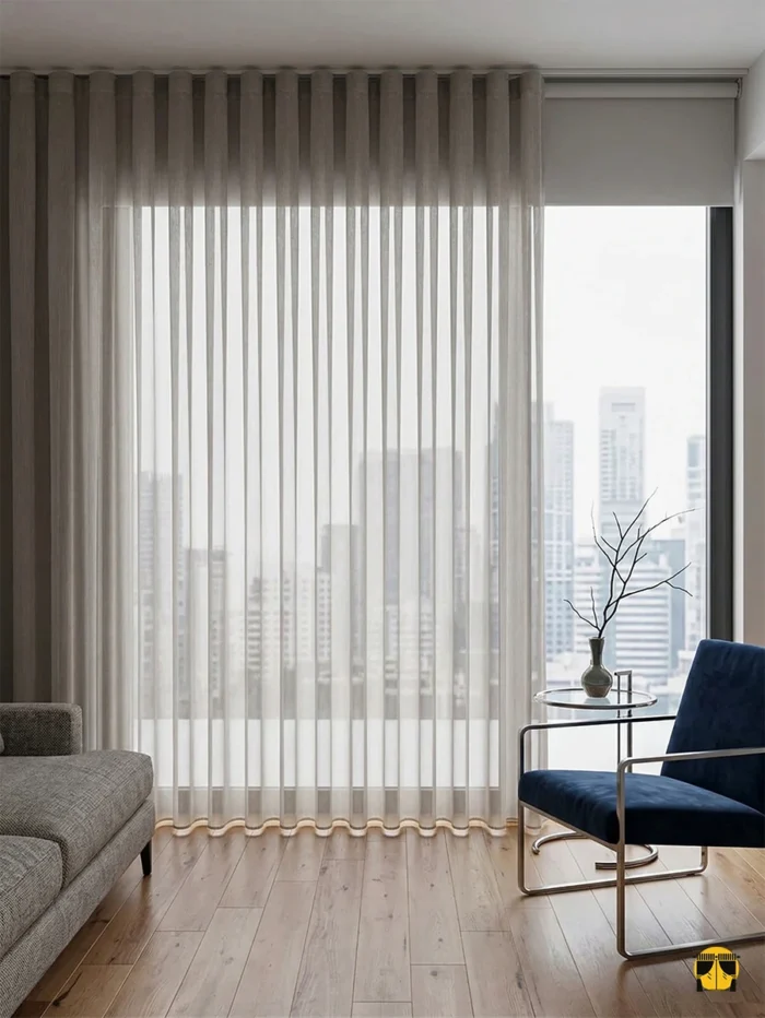 Siyah metal rustiklerle kombinlenmiş, sık pileleri sayesinde birer mimari sütun gibi muntazam inen dökümlü gri zırh tül perde sergisi