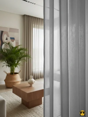 Modern bir pencere önünde, zemine kadar uzanan, açık gri tonunda, sık dokulu, tok ve düzenli pileli modern zırh tül perde.