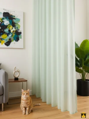 Modern bir oturma odası penceresinde, tavandan yere kadar uzanan, üzerinde zarif ve silik dikey çizgiler bulunan, yeşil tonlarında, tok dökümlü ve ferahlatıcı şık tül perde.