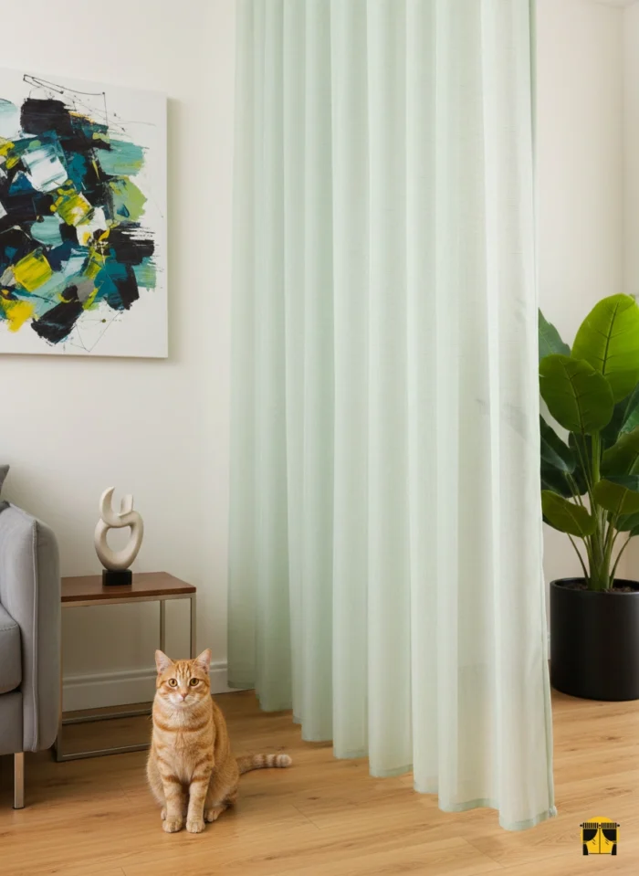 Modern bir oturma odası penceresinde, tavandan yere kadar uzanan, üzerinde zarif ve silik dikey çizgiler bulunan, yeşil tonlarında, tok dökümlü ve ferahlatıcı şık tül perde.