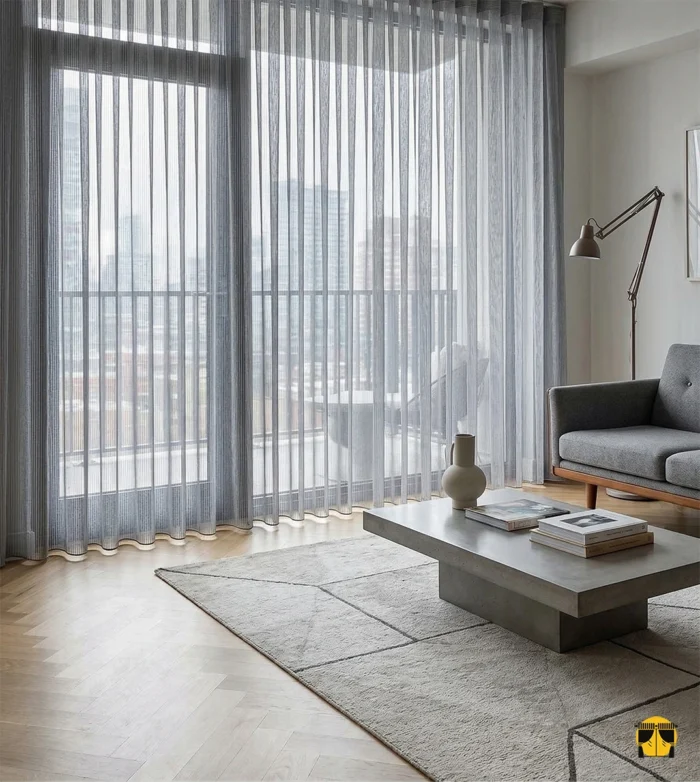 Gri dikine çizgili tül perdenin dokusu arasından süzülen güneş ışığının, oda içerisinde yarattığı modern, çizgisel ve gümüşi aydınlık