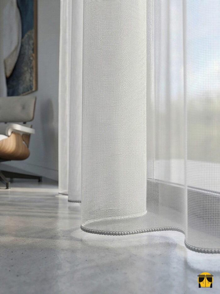 Doku Detayı: "İlyada serisinin açık gri tonundaki belirgin keten lif yapısını ve mat yüzeyini sergileyen yakın plan çekimi; pencereler için kaliteli ve dökümlü tül perde karakteri."