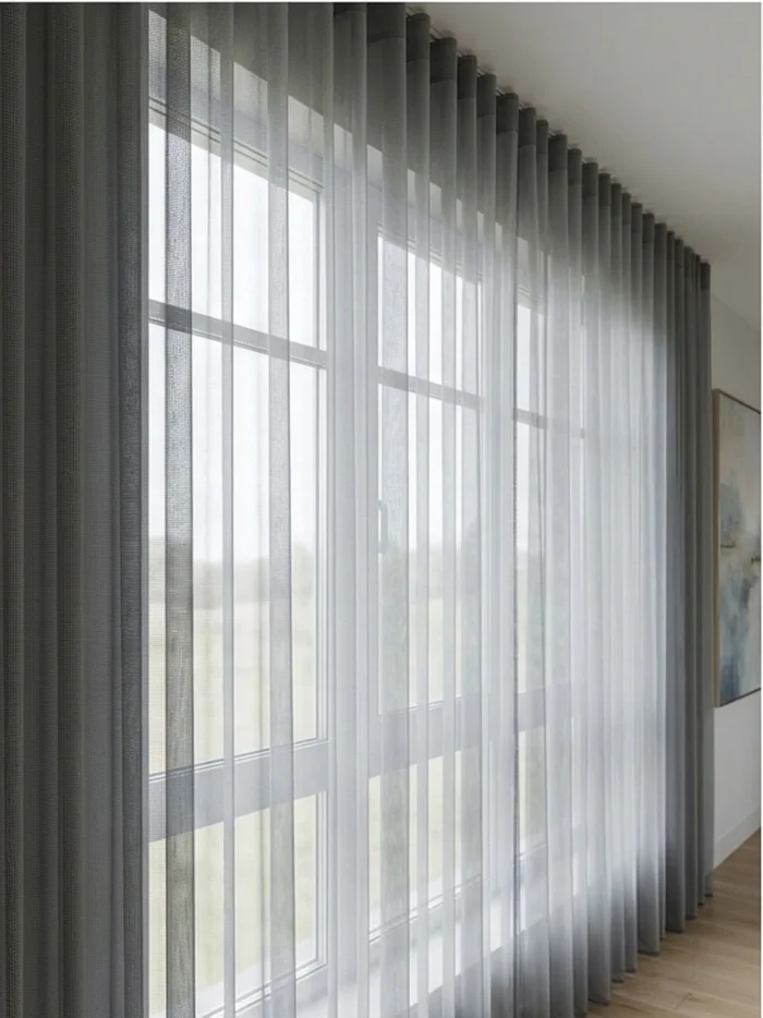 Mekan Tasarımı: "Antrasit fon perdeler ve metalik aksesuarlarla dekore edilmiş loft bir salonda, pencerelere mimari bir derinlik katan gri keten tül perde tasarımı."