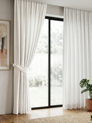 "Yüksek kaliteli dokuma teknolojisiyle üretilmiş açık krem tonundaki pürüzsüz fon perde kumaşını ve dökümlü yapısını sergileyen yakın plan."