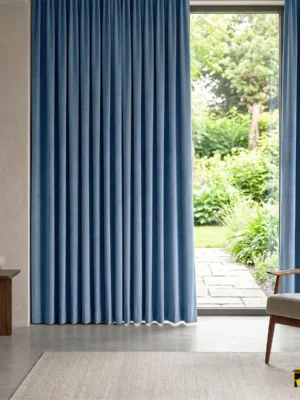 Beyaz mobilyalar ve gümüş aksesuarlarla dekore edilmiş modern bir salonda, pencerelere tazeleyici bir odak noktası katan açık mavi fon perde tasarımı