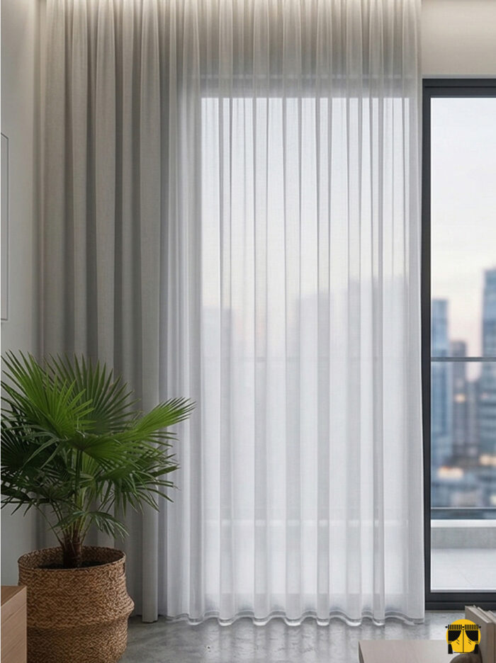 Doku Detayı: "Krep dokuma teknolojisiyle üretilmiş açık gri tonundaki pütürlü yüzeyi ve kaliteli lif yapısını sergileyen yakın plan çekimi; pencereler için modern tül perde karakteri."