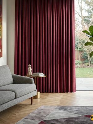 Gri mobilyalarla çarpıcı bir kontrast oluşturan, pencerelere hem termal yalıtım hem de dinamik bir karakter kazandıran mat dokulu fuşya karartma perd