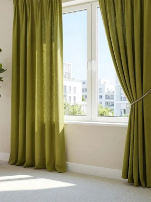 Gri ve antrasit mobilyalarla çarpıcı bir kontrast oluşturan, pencerelere bahar enerjisi katan mat yüzeyli fıstık yeşili perde detayı