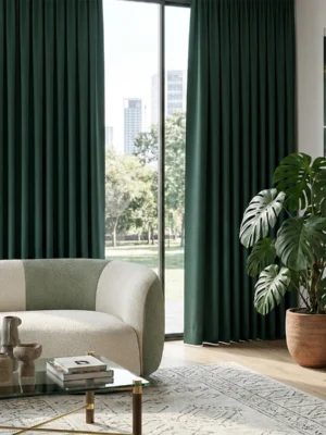 Güneş ışığını tamamen engelleyerek huzurlu bir uyku ortamı yaratan, tok dökümlü ve mat yüzeyli koyu yeşil blackout fon perde detayı.