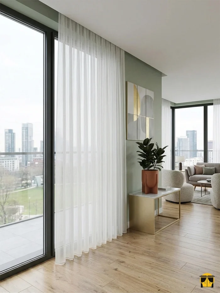 "Bej mobilyalar ve ahşap detaylarla dekore edilmiş modern bir salonda, pencerelere sıcaklık ve zarafet katan Riro ekru tül perde tasarımı."