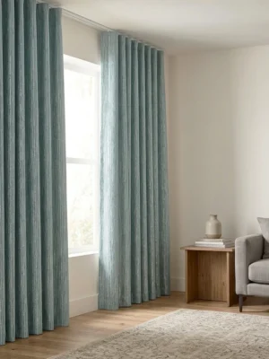 Modern bir salonda, Lante Açık Mavi jakar desenli fon perde ve sade tül ile oluşturulmuş, sofistike ve dokulu bir pencere tasarımı