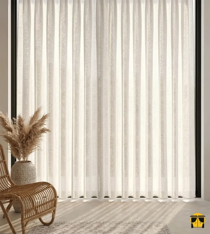 Krem rengi kalın keten kumaşın doğal ve gözenekli lifleri arasından süzülen güneş ışığının, oda içerisinde yarattığı yumuşak, mat ve davetkar aydınlık."