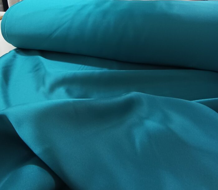 Modern salonlarda gri ve beyaz mobilyalarla mükemmel bir kontrast oluşturan dökümlü turkuaz saten fon perde.