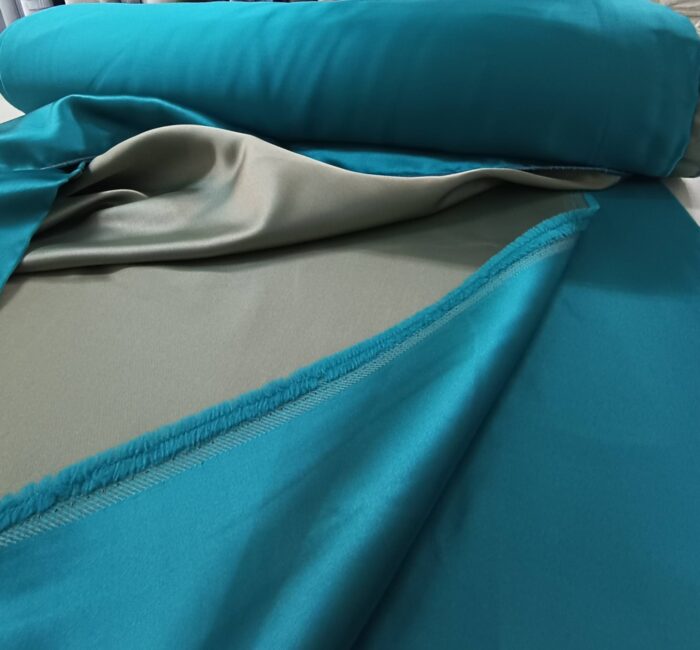 Yüksek kaliteli saten dokuma kumaşın pürüzsüz dokusunu gösteren turkuaz mavi fon perde yakın çekim görseli.