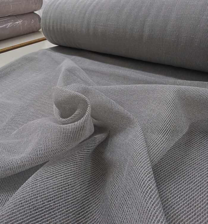 İskandinav tarzı oturma odasında gün ışığını filtreleyen gri keten tül.