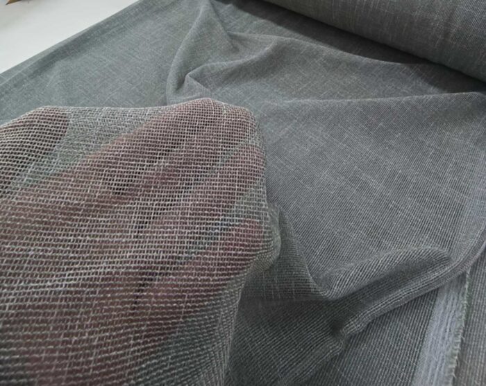 Gün ışığını filtreleyen koyu yeşil keten tül perdenin oda içindeki duruşu.