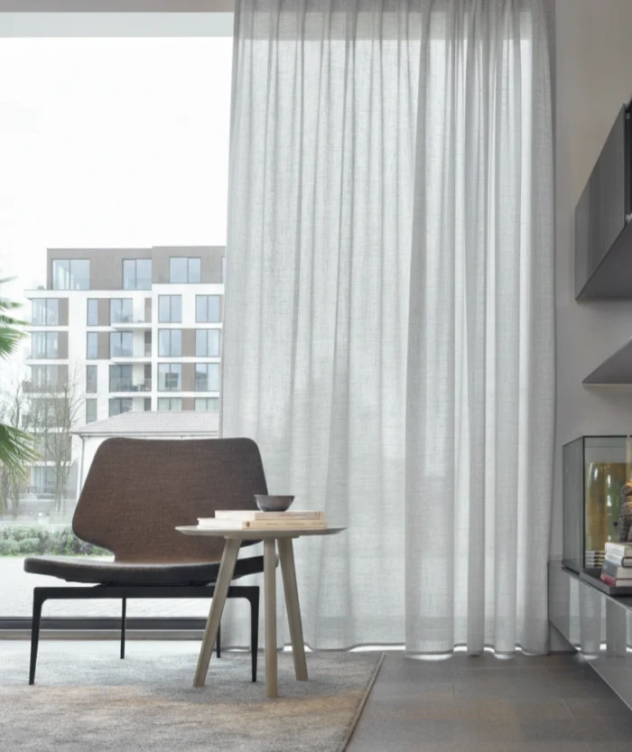 Modern bir salonda antrasit koltuklarla kombinlenmiş kalın dokulu gri tül perde.