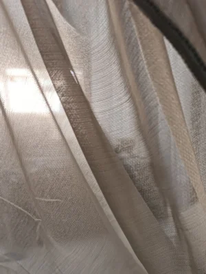 Pencereden sızan güneş ışığını estetik bir şekilde filtreleyen bej krem düz tül perde çekimi