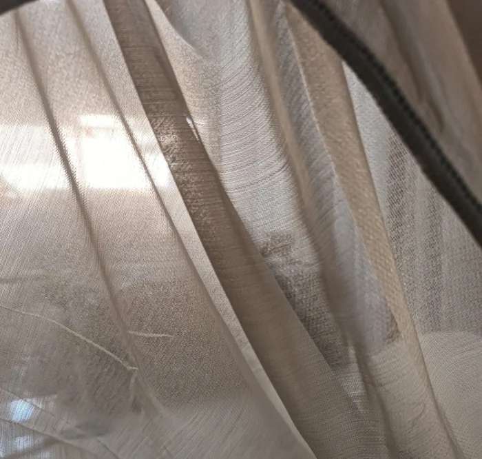 Pencereden sızan güneş ışığını estetik bir şekilde filtreleyen bej krem düz tül perde çekimi