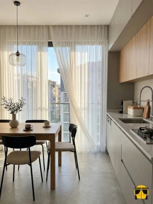 Panama keteni krem tül fon perdenin gözenekli lifleri arasından süzülen güneş ışığının, mutfakta yarattığı sıcak, rüstik ve samimi aydınlık