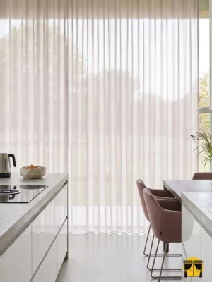 Açık lila mutfak tül perdesinin ince dokusu arasından süzülen güneş ışığının, mutfakta yarattığı ferah, lavanta tonlarında ve huzurlu aydınlık