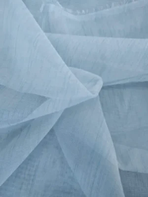 Işık ve Atmosfer: "Açık mavi keten mutfak tül perdesinin doğal gözenekleri arasından süzülen güneş ışığının, mutfakta yarattığı ferah, gökyüzü tonlarında ve huzurlu aydınlık."