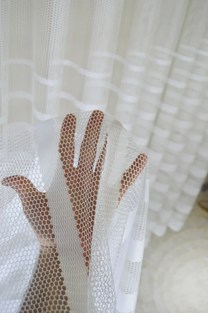 Dikey şerit desenli file (mesh) kumaşın gözenekli yapısını ve beyaz dokuma detaylarını sergileyen yakın plan çekimi; mutfaklar için havadar tekstür.