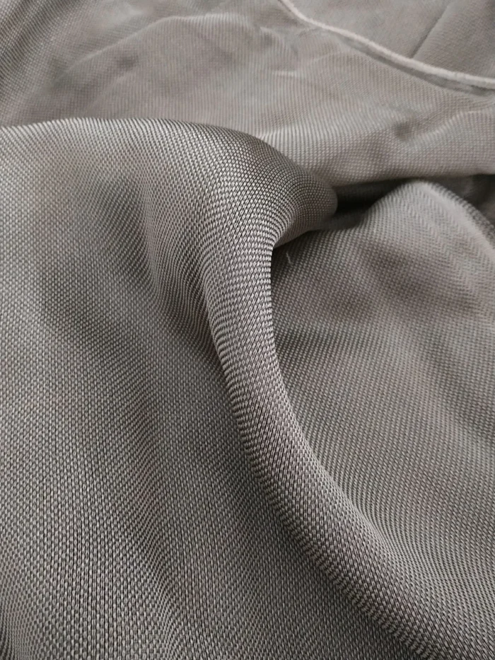 Ağır dökümü sayesinde rüzgarda zarifçe süzülen, ütü gerektirmeyen ve modern bir endüstriyel şıklık sunan kaliteli kurşun rengi mutfak tül perde detayı.