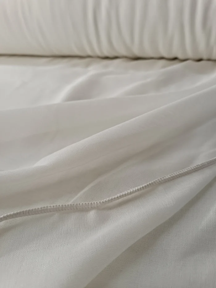 "Mutfak pencerelerinde mahremiyeti artıran sık ilmekli yapısı ve gün ışığını asilce süzme özelliğiyle modern krem tül perde görseli."