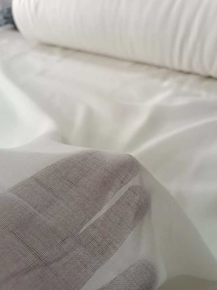 "Kahverengi fon perdelerle kombinlenmiş, ilmekli yapısı sayesinde pencerelerde zengin bir duruş sergileyen krem keten tül perde uygulaması."