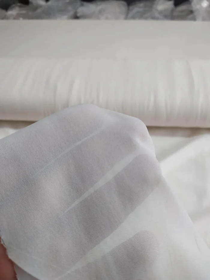 "Bej krep düz mutfak tül perdesinin kumsu dokusu arasından süzülen güneş ışığının, mutfakta yarattığı sıcak ve organik aydınlık."