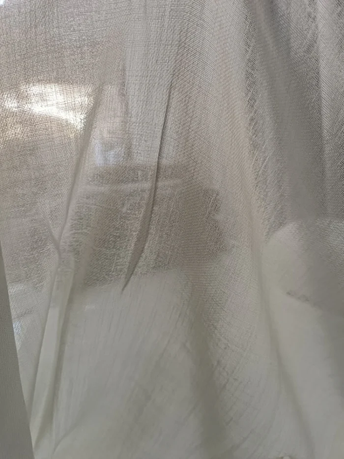 "Ağır dökümü sayesinde rüzgarda formunu bozmayan ve mutfak buharına dayanıklı, profesyonel dikim hasır detaylı koyu krem tül perde detayı."