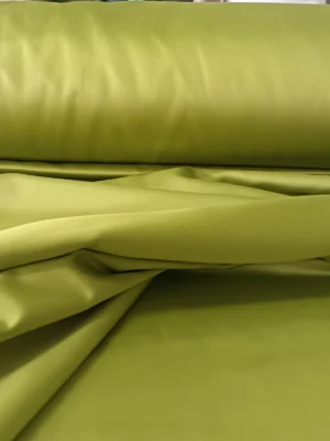 "Optik beyaz tüllerle birlikte kullanılan, ağır dökümü sayesinde pencerelerde lüks bir duruş sergileyen parlak yeşil saten perde uygulaması."