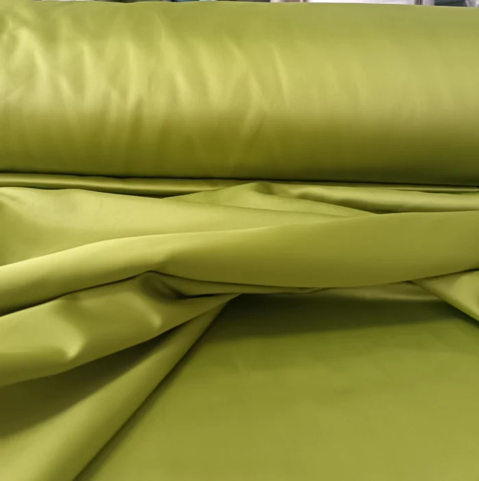 "Optik beyaz tüllerle birlikte kullanılan, ağır dökümü sayesinde pencerelerde lüks bir duruş sergileyen parlak yeşil saten perde uygulaması."