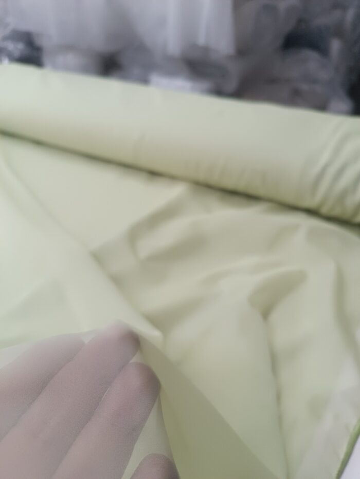 "Geniş salon pencerelerinde tavandan yere kadar uzanan, dökümlü ve nizamlı duran sık pileli açık yeşil rüstik düz tül tasarımı."