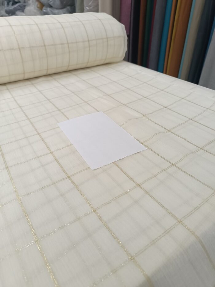 "Vizon tonları ve parlak pirinç oturma odası tekstil ürünleriyle kusursuz uyum yakalayan altın çizgili krem keten tül perde."