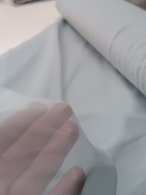 "Geniş salon pencerelerinde tavandan yere kadar uzanan, dökümlü ve nizamlı duran sık pileli buz mavi rüstik düz tül tasarımı."