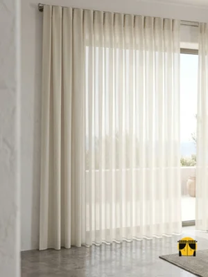 "Soria krem düz tül perdenin pürüzsüz mat dokusu ve sıcak fildişi tonunun modern bir salonda yarattığı rafine, ferah ve minimalist atmosfer."